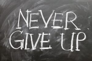 White letters on a black chalkboard that say "never give up"